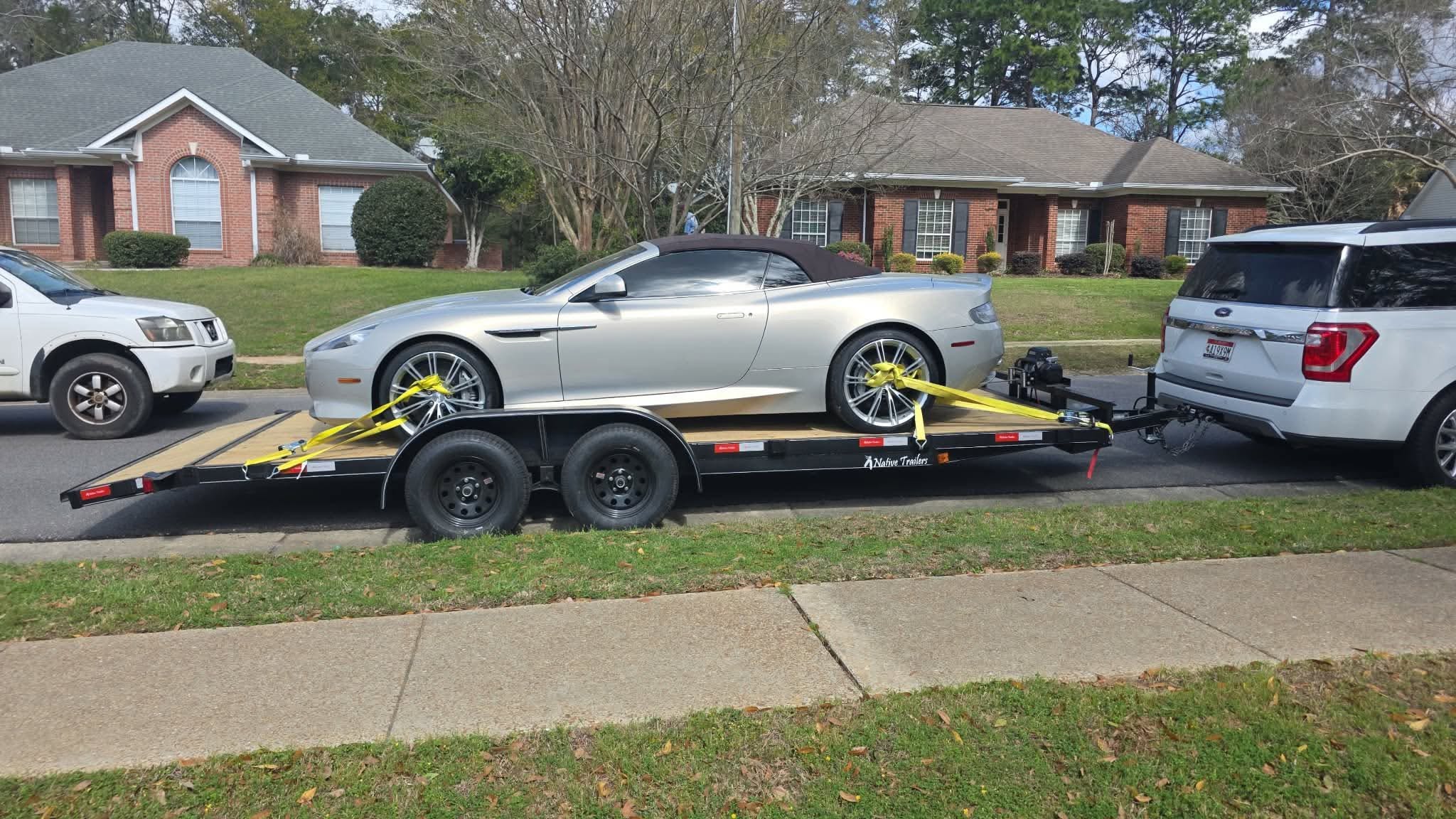 Convertible sports car strapped down on the wood deck car hauler